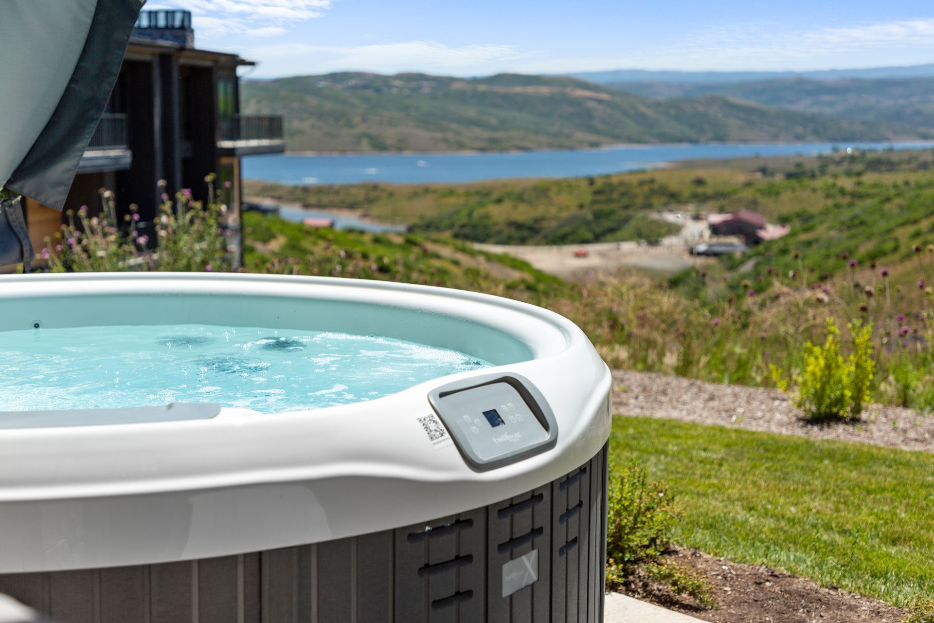 Hot tub overlooking a lake and mountains on a sunny day.