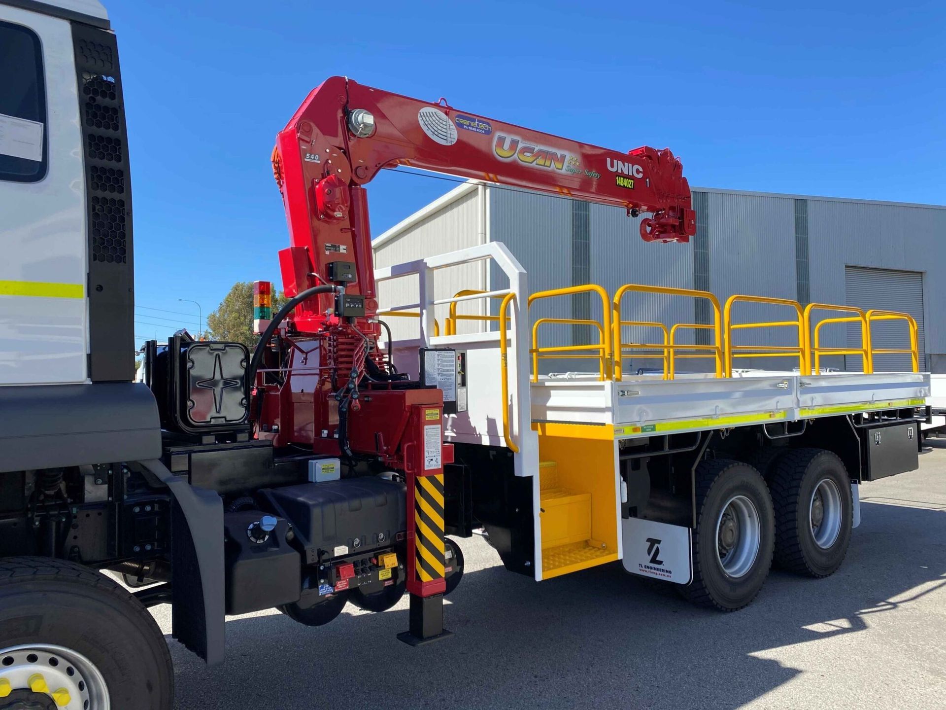 a man is standing next to a truck with a crane attached to it .