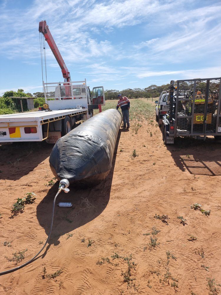a man is standing next to a crane truck with marine airbags on the ground