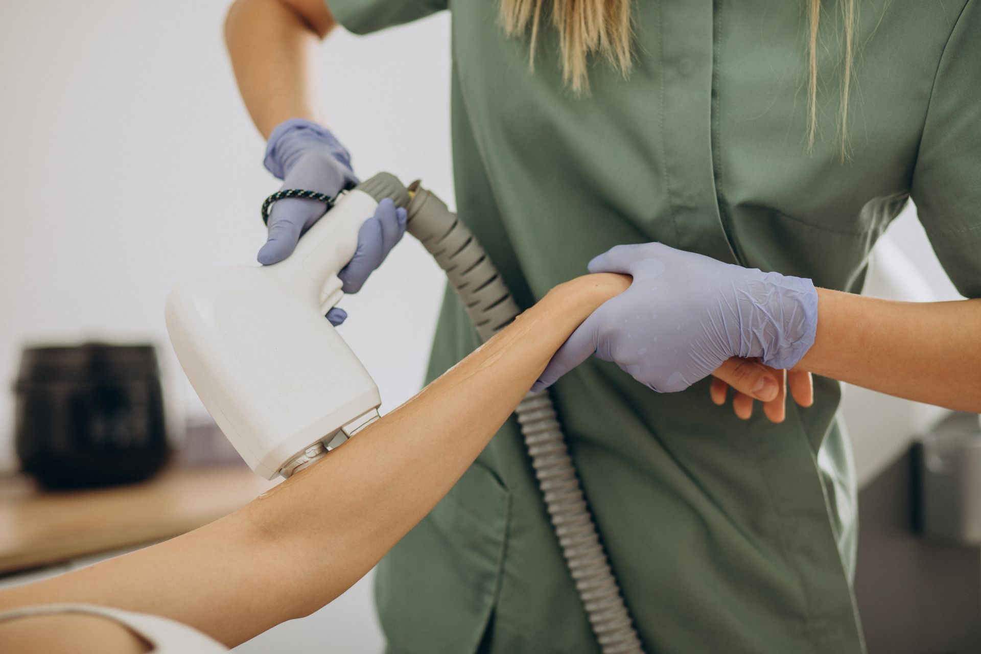 A woman is getting a laser hair removal treatment on her arm.