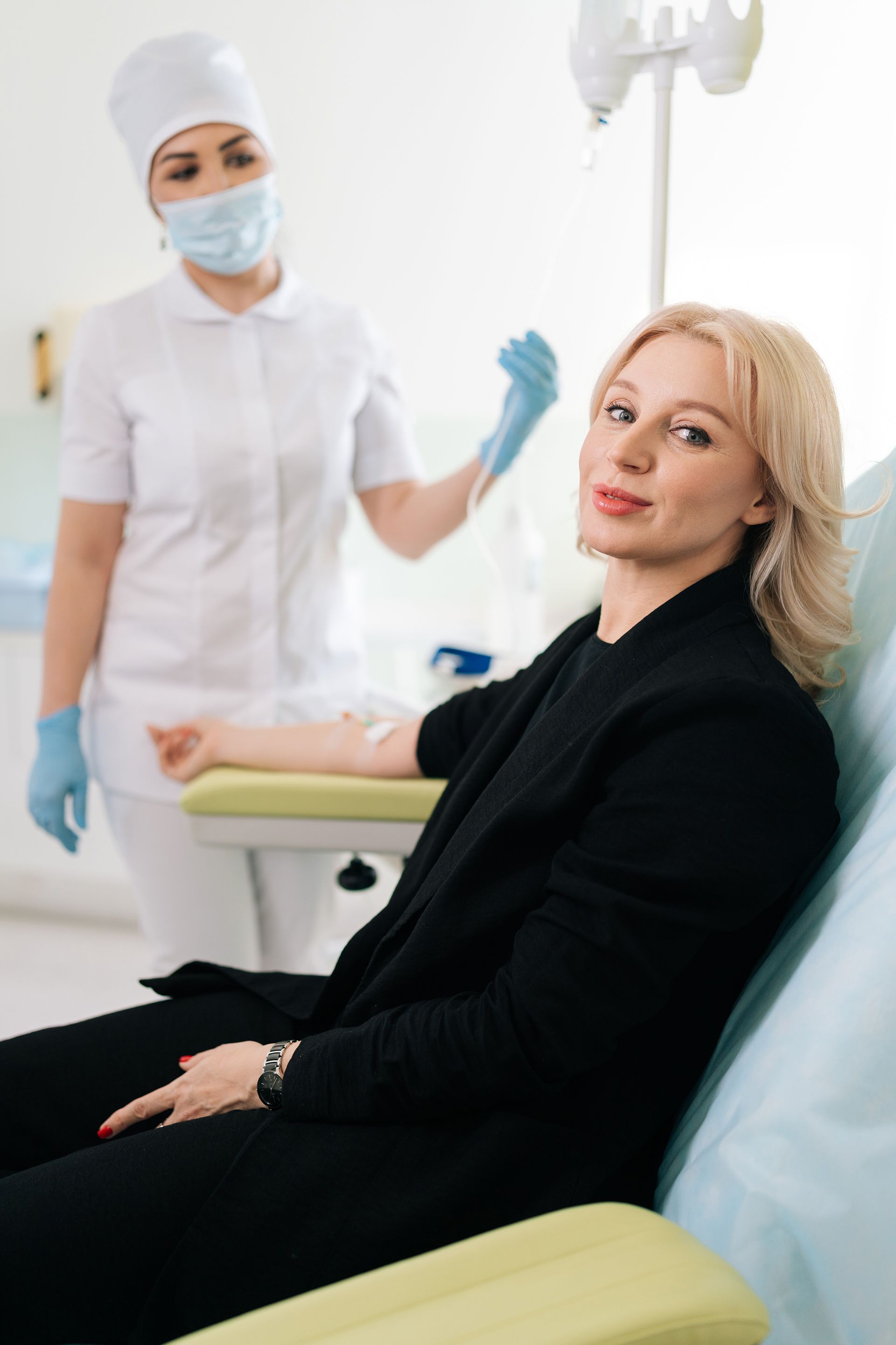 A woman is sitting in a dental chair with a nurse standing behind her.