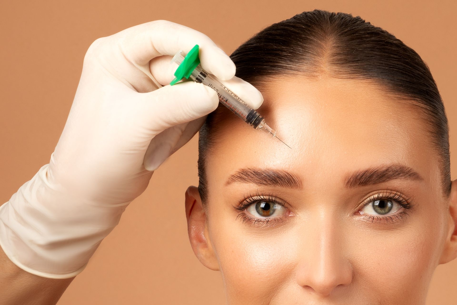 A woman is getting a botox injection in her forehead.