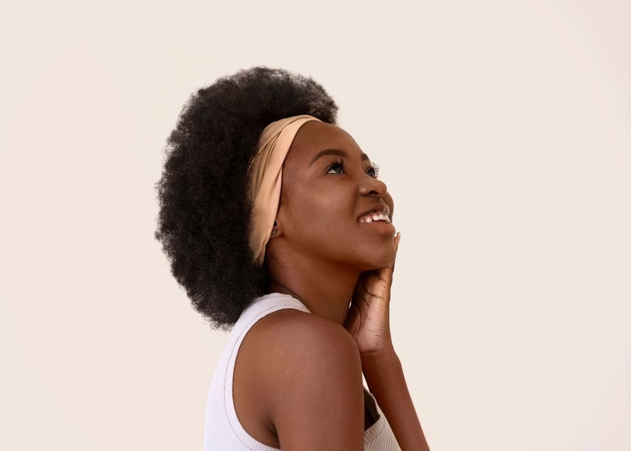 A woman wearing a headband is smiling and looking up.