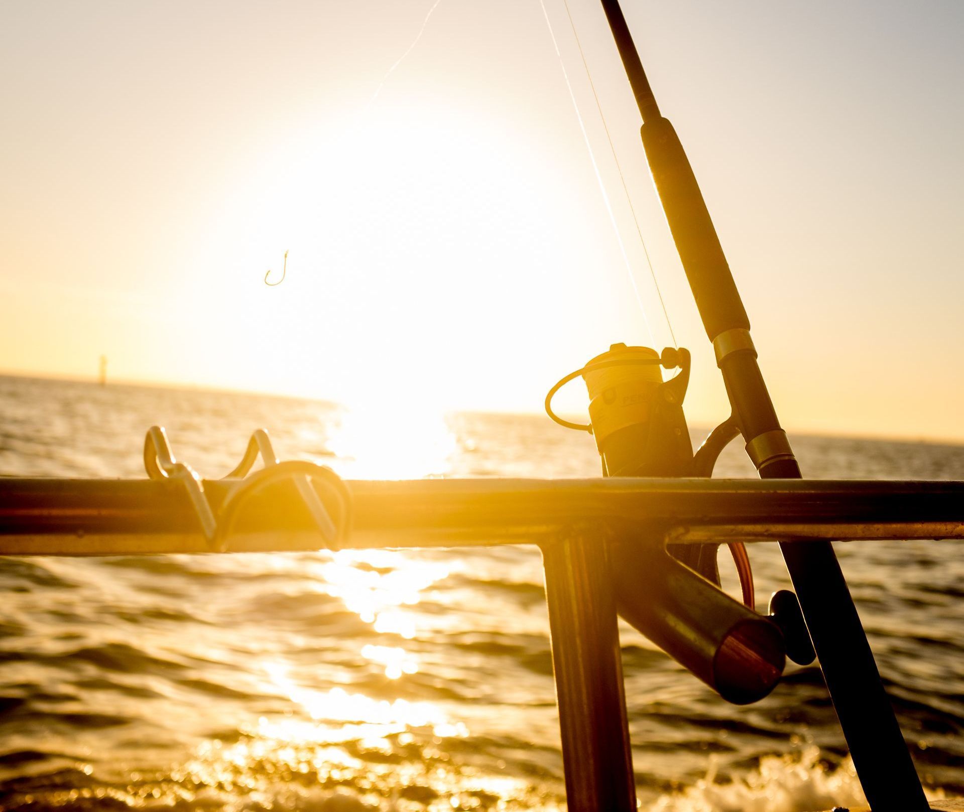A fishing rod is sitting on a boat in the water at sunset