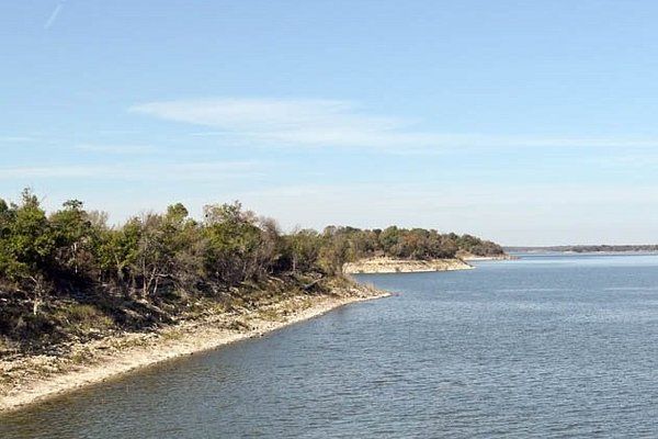 A large body of water surrounded by trees on a sunny day.