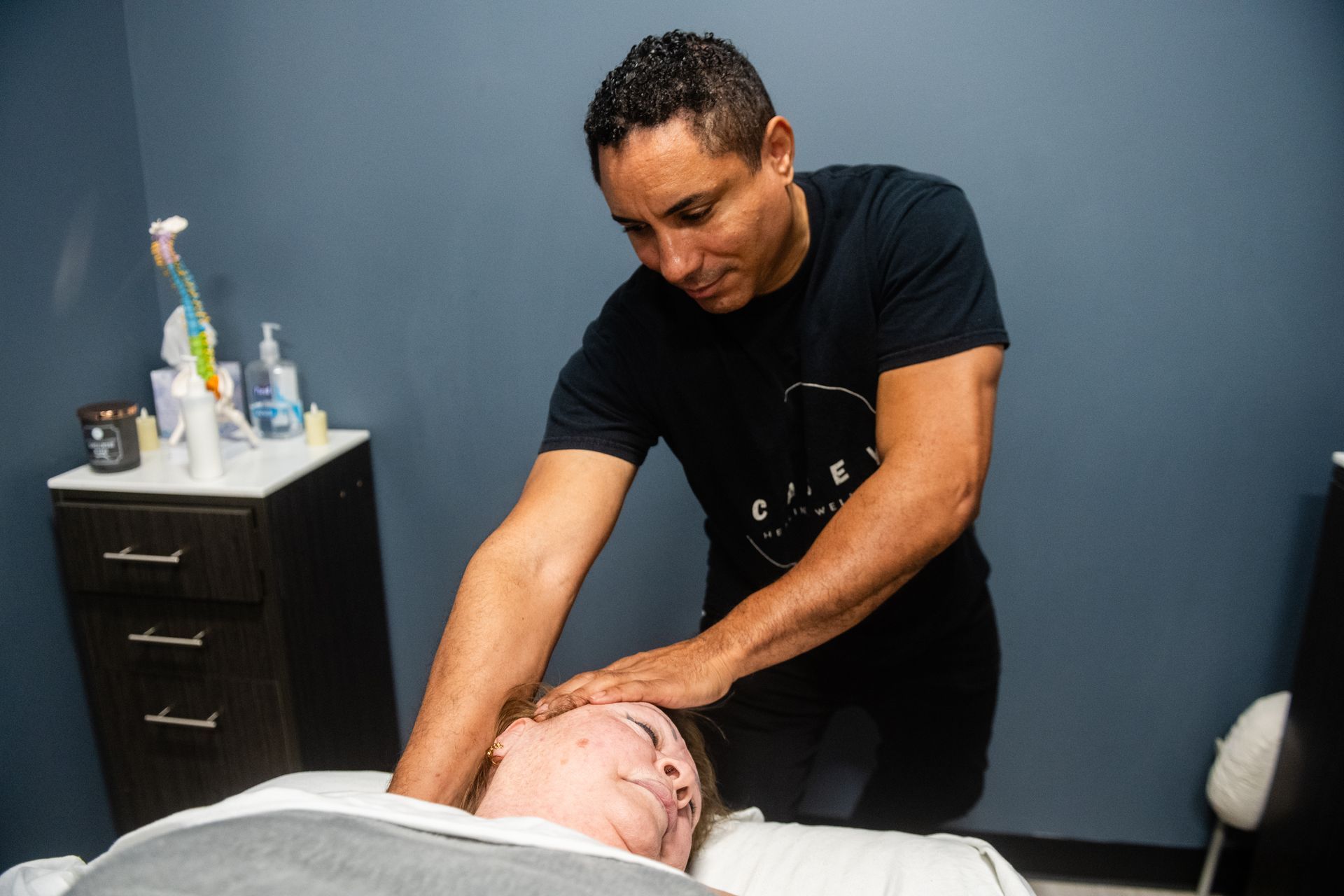 A woman is sitting on a table while another woman stretches her arms.