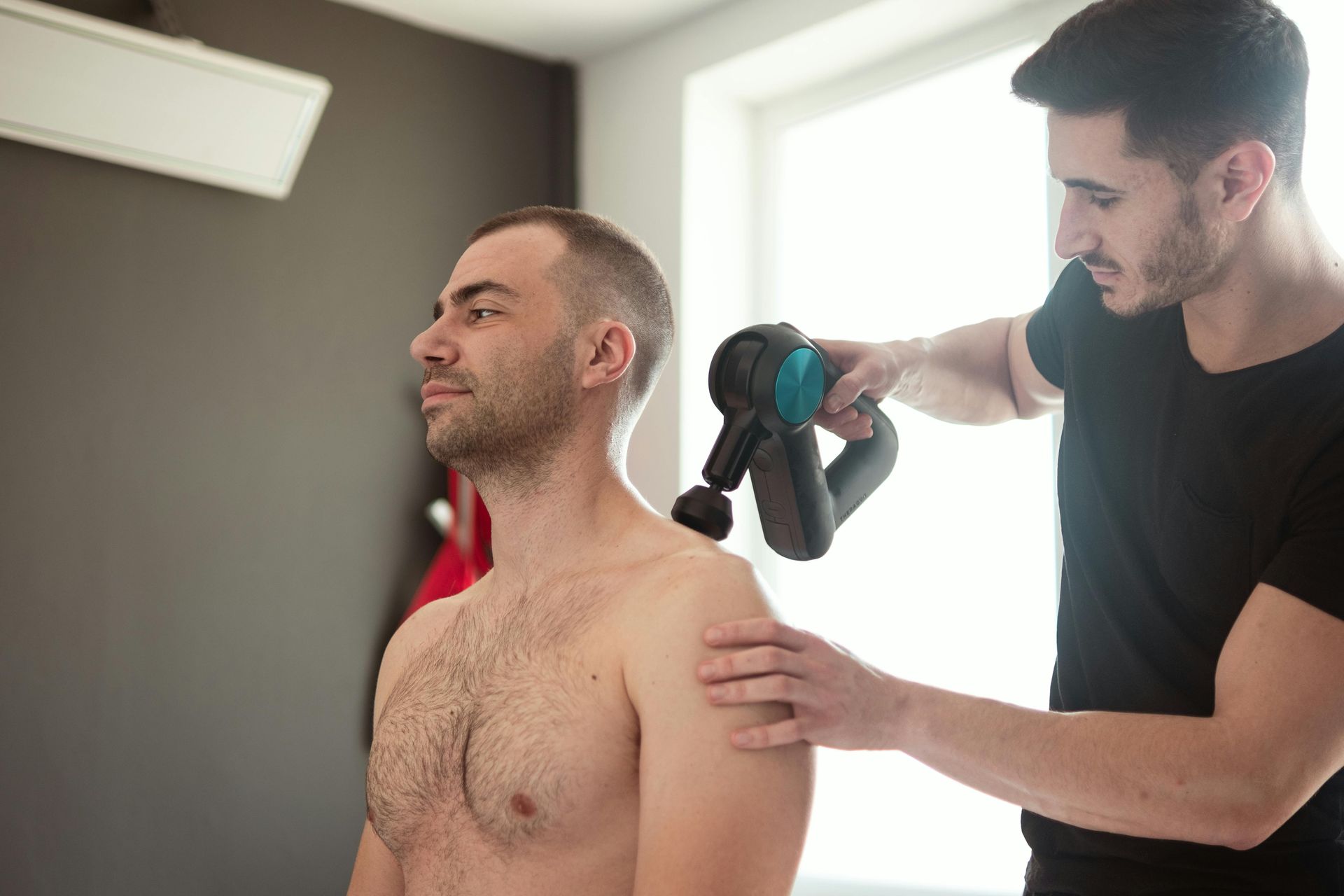 A man without a shirt is getting a massage from another man.