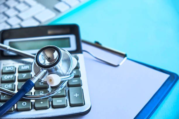 A stethoscope is sitting on top of a calculator on a clipboard.