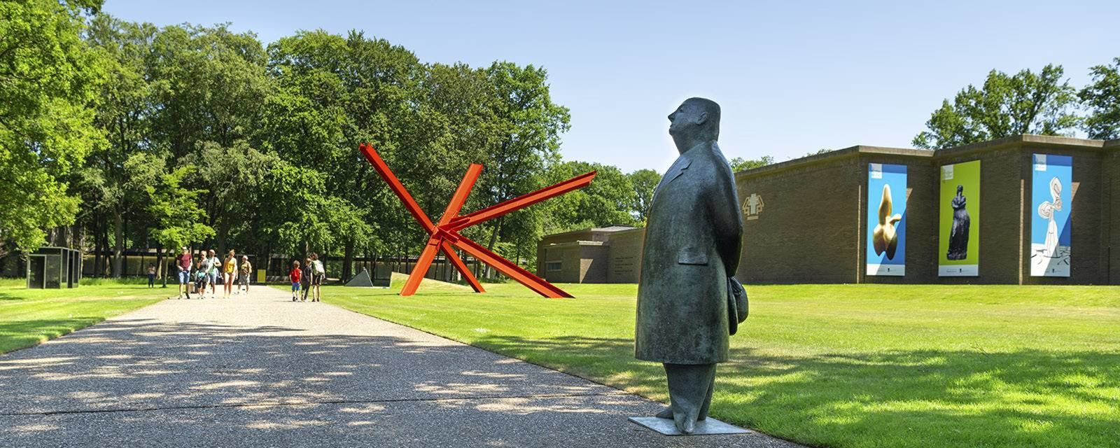 A statue of a man standing in front of a building in a park.