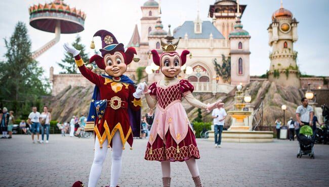 A couple of mascots standing next to each other in front of a castle.