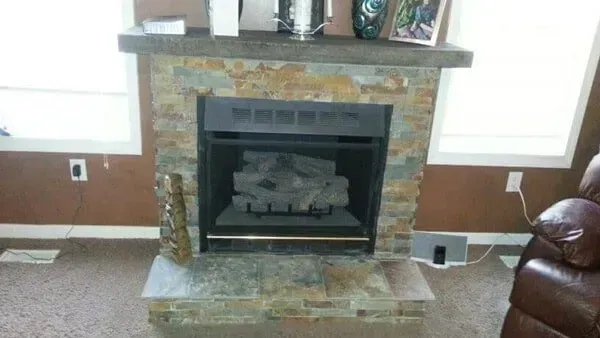 Fireplace with stone facade, gray hearth, brown walls, and windows on either side.