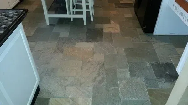 Slate tile kitchen floor with white cabinets and a partial view of a kitchen island.