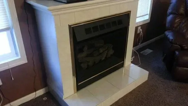 White tiled electric fireplace in a room with brown walls and carpet.