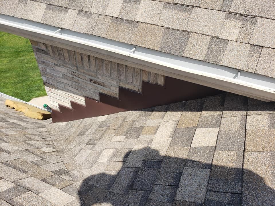 Roofing detail: brown metal flashing at roof valley and gutter, with shingles in view.