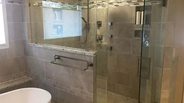 Bathroom with a large, glass-enclosed shower, neutral-toned tiles, and a white soaking tub.