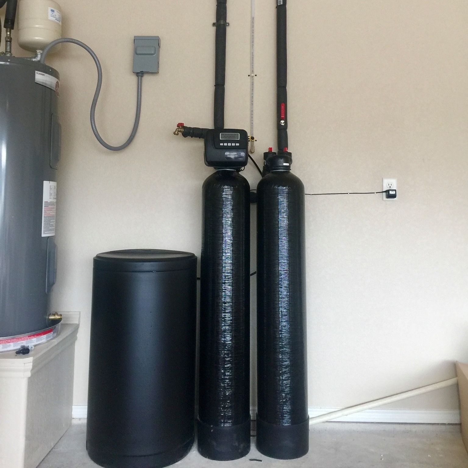 Two black water filters are sitting next to each other in a room.