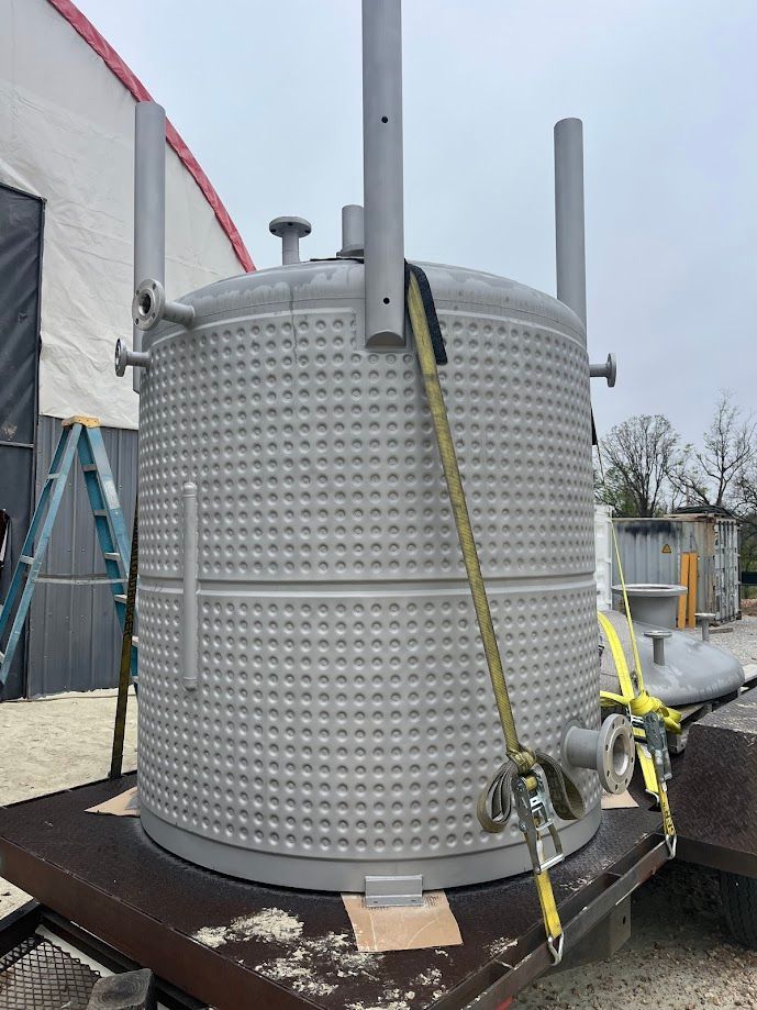 A large stainless steel tank is sitting on top of a wooden table.