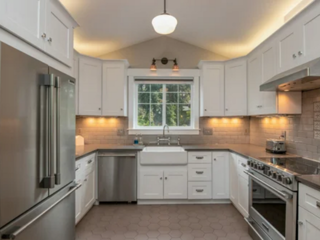 Bright, white kitchen with stainless steel appliances, white cabinets, and a window.