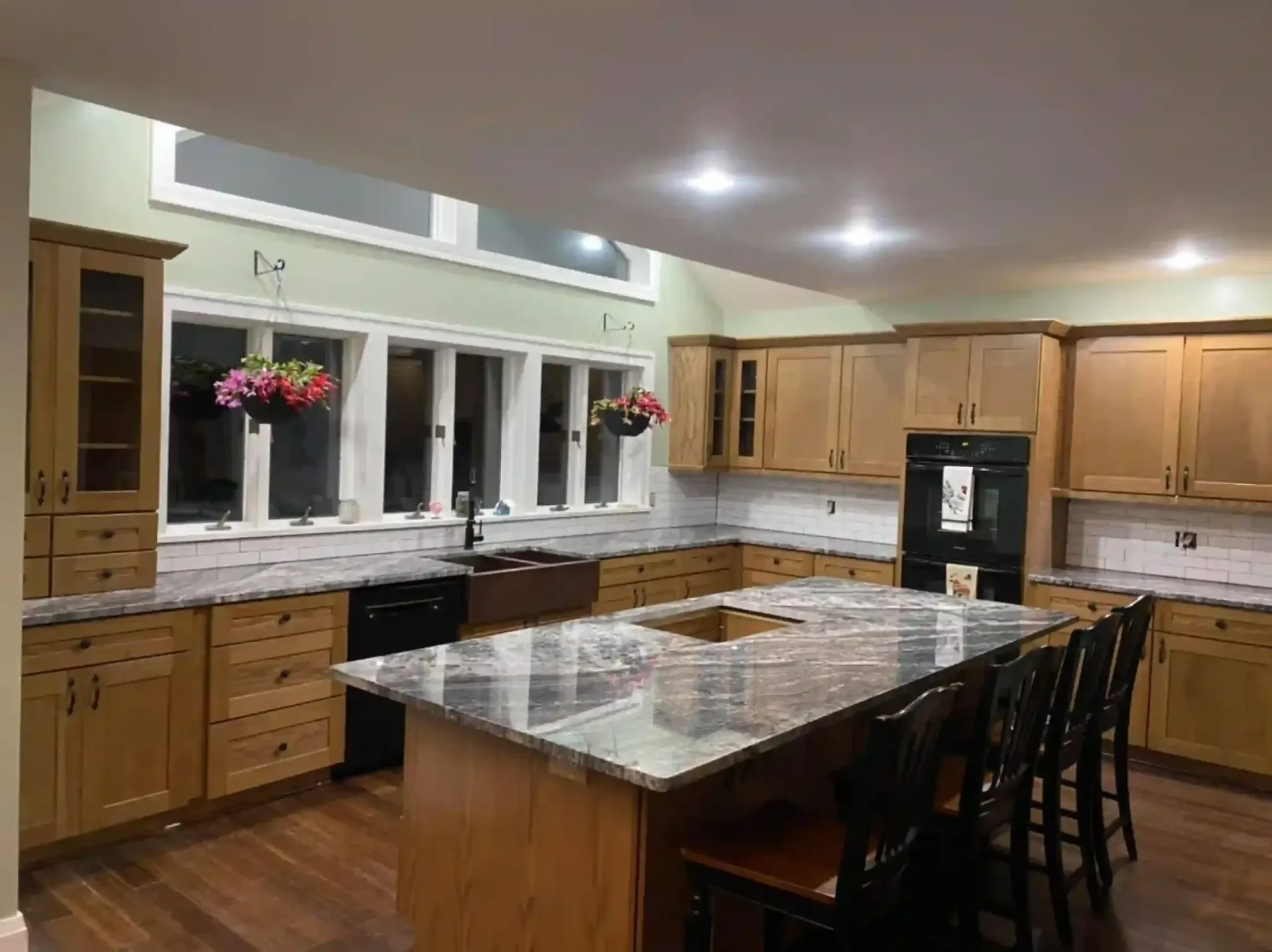 Spacious kitchen with wood cabinets, island, black appliances, and granite countertops