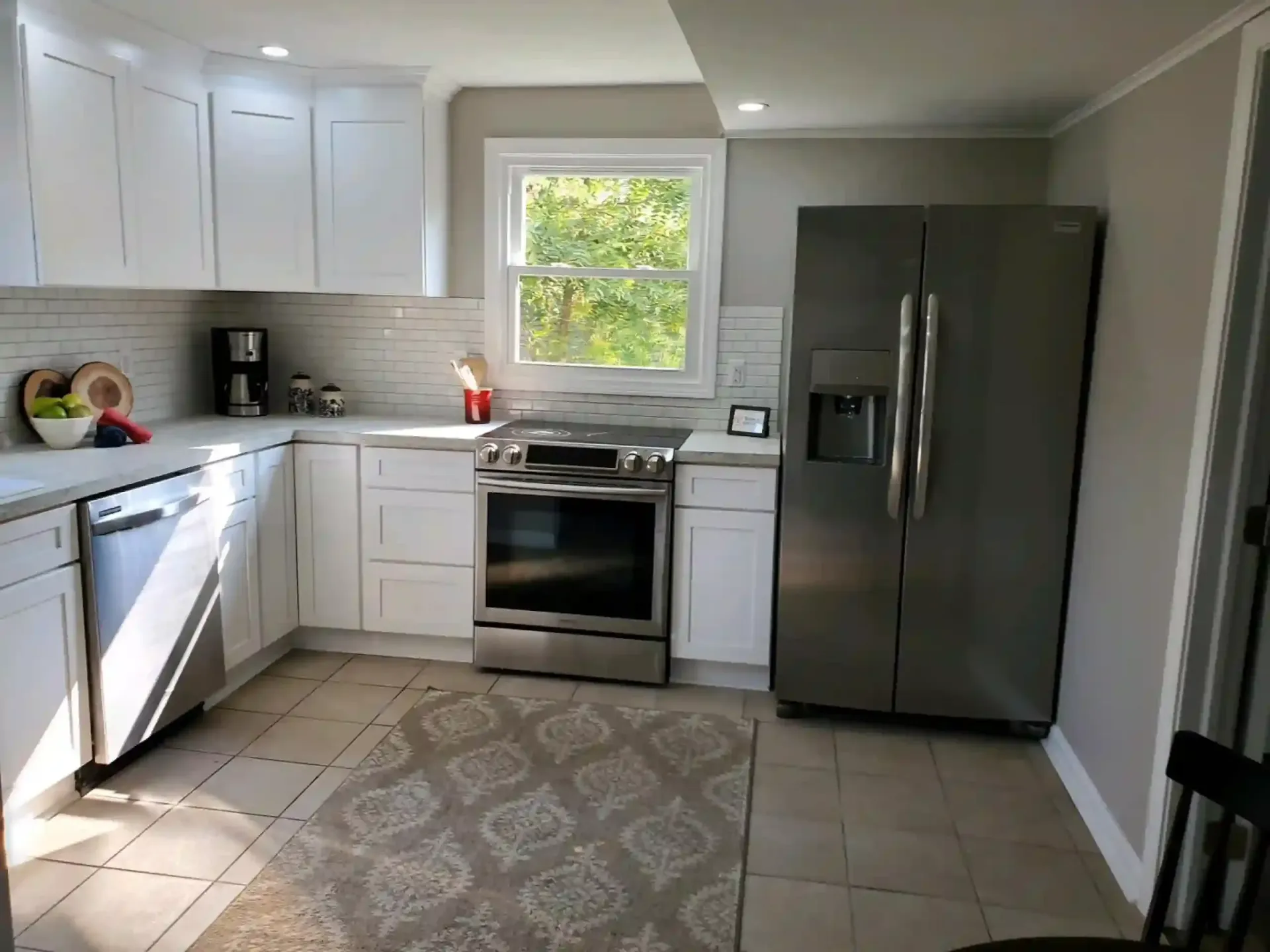 White kitchen with stainless steel appliances, light countertops, and neutral-colored walls and floor.