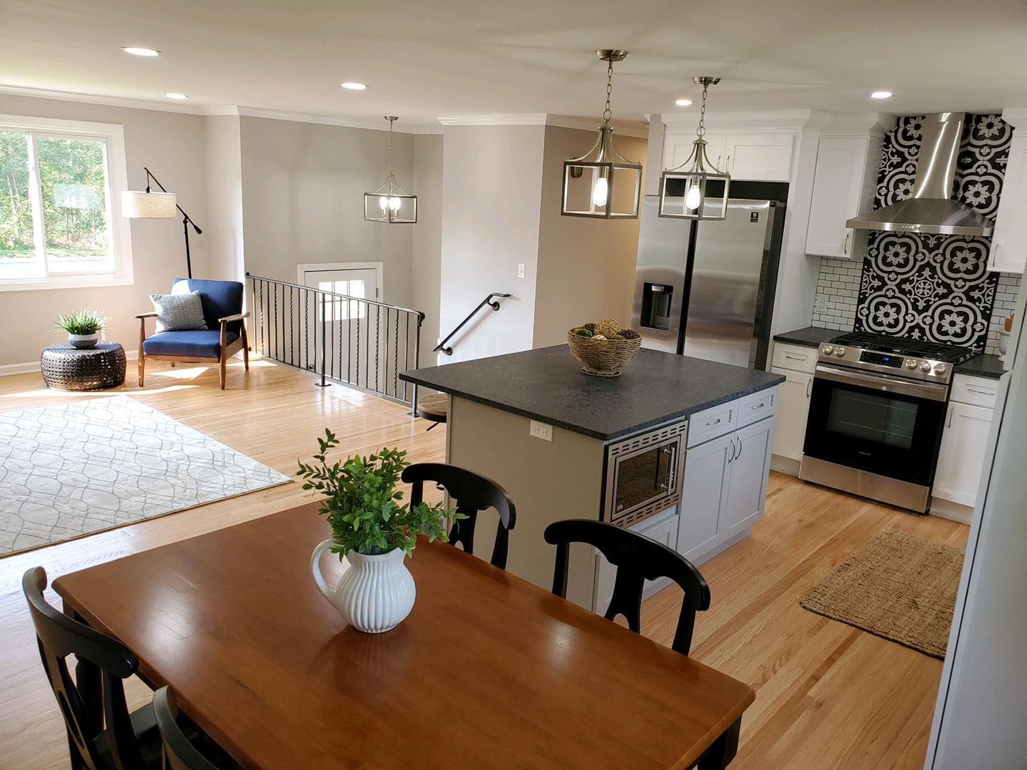 Open-concept kitchen and living area, including a dining table, island, and stairs.