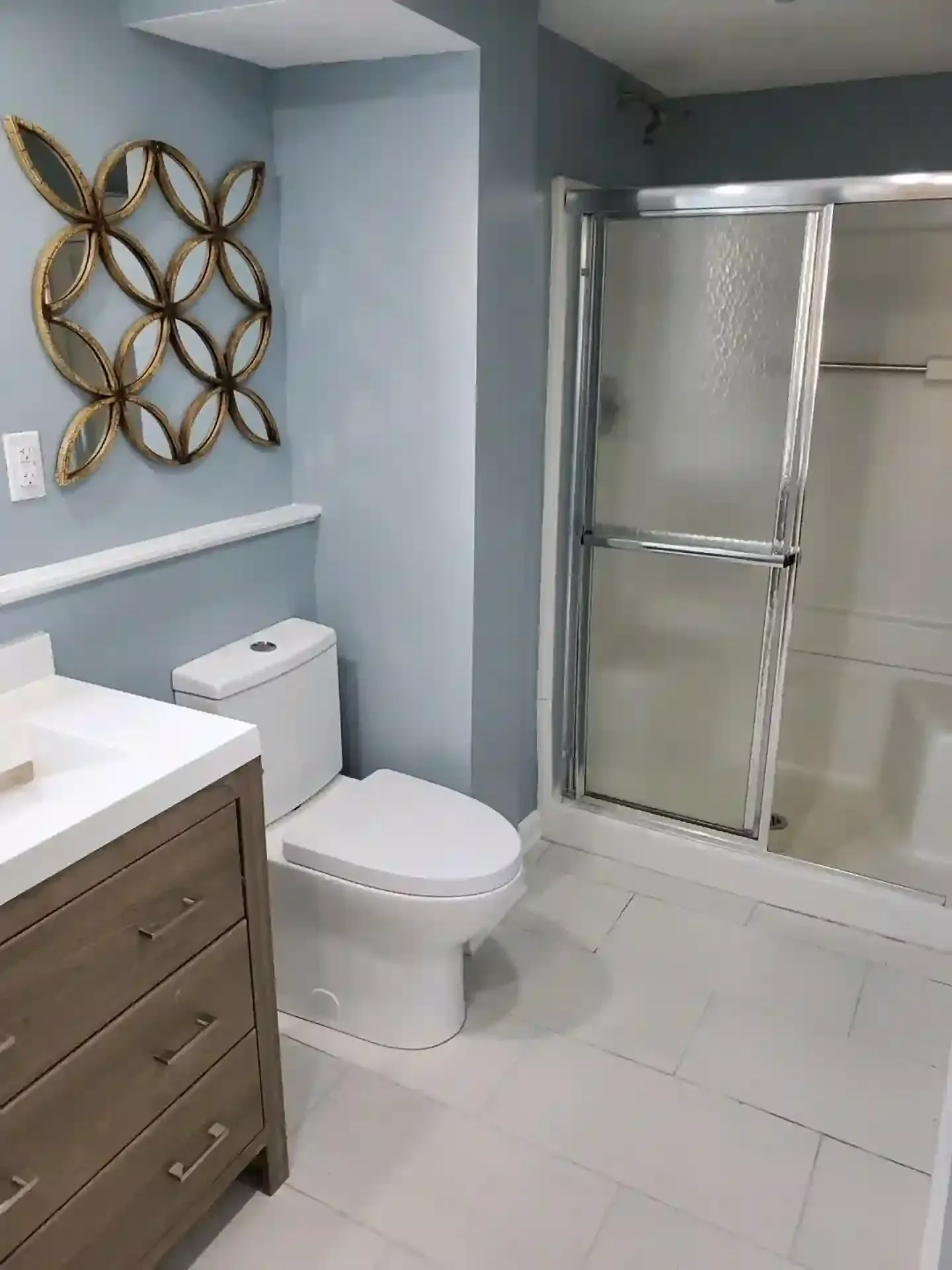 Bathroom with blue walls, white toilet, vanity, and a shower with sliding glass doors.
