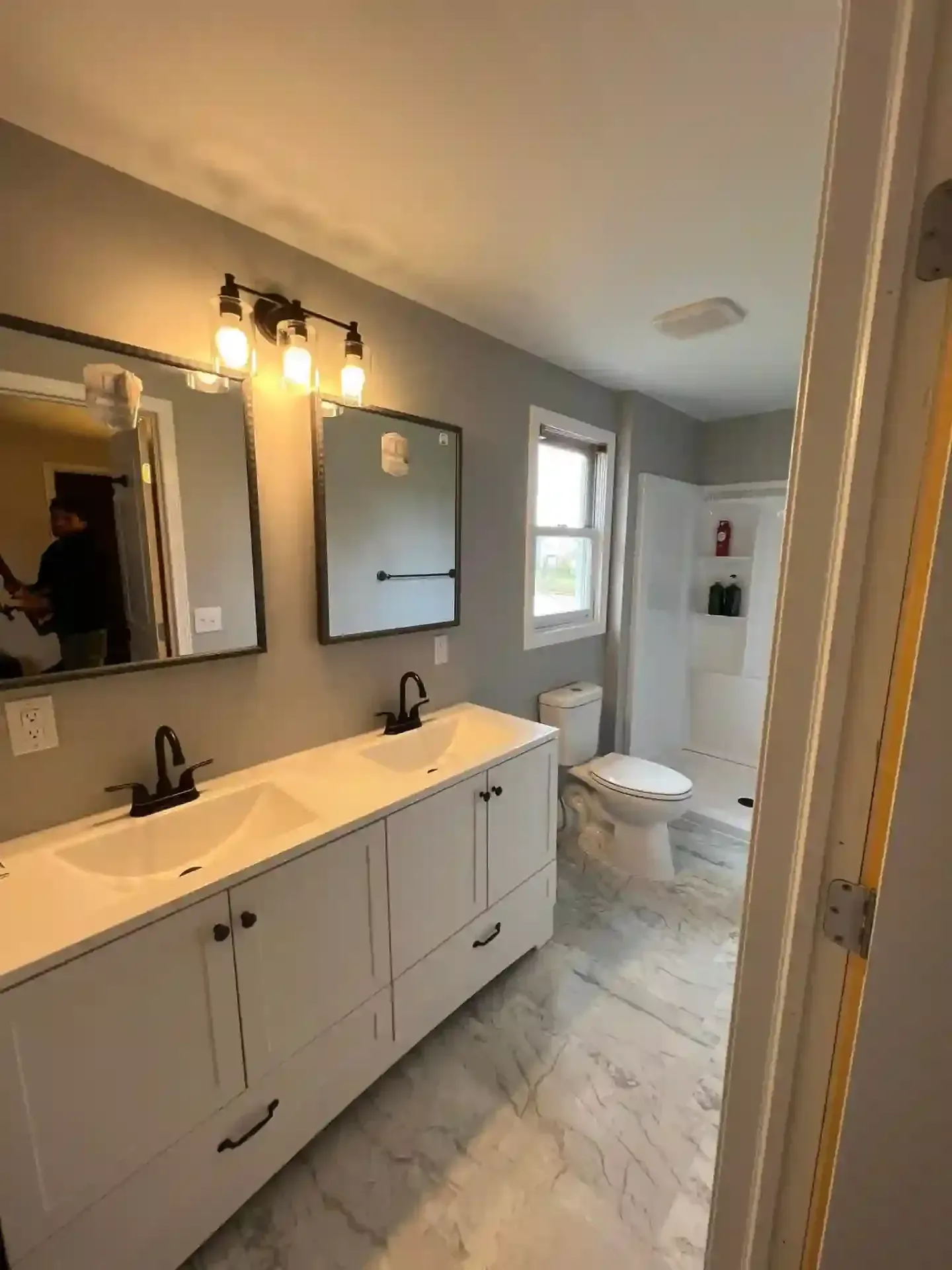 Bathroom with a double vanity, large mirrors, a toilet, and a shower.