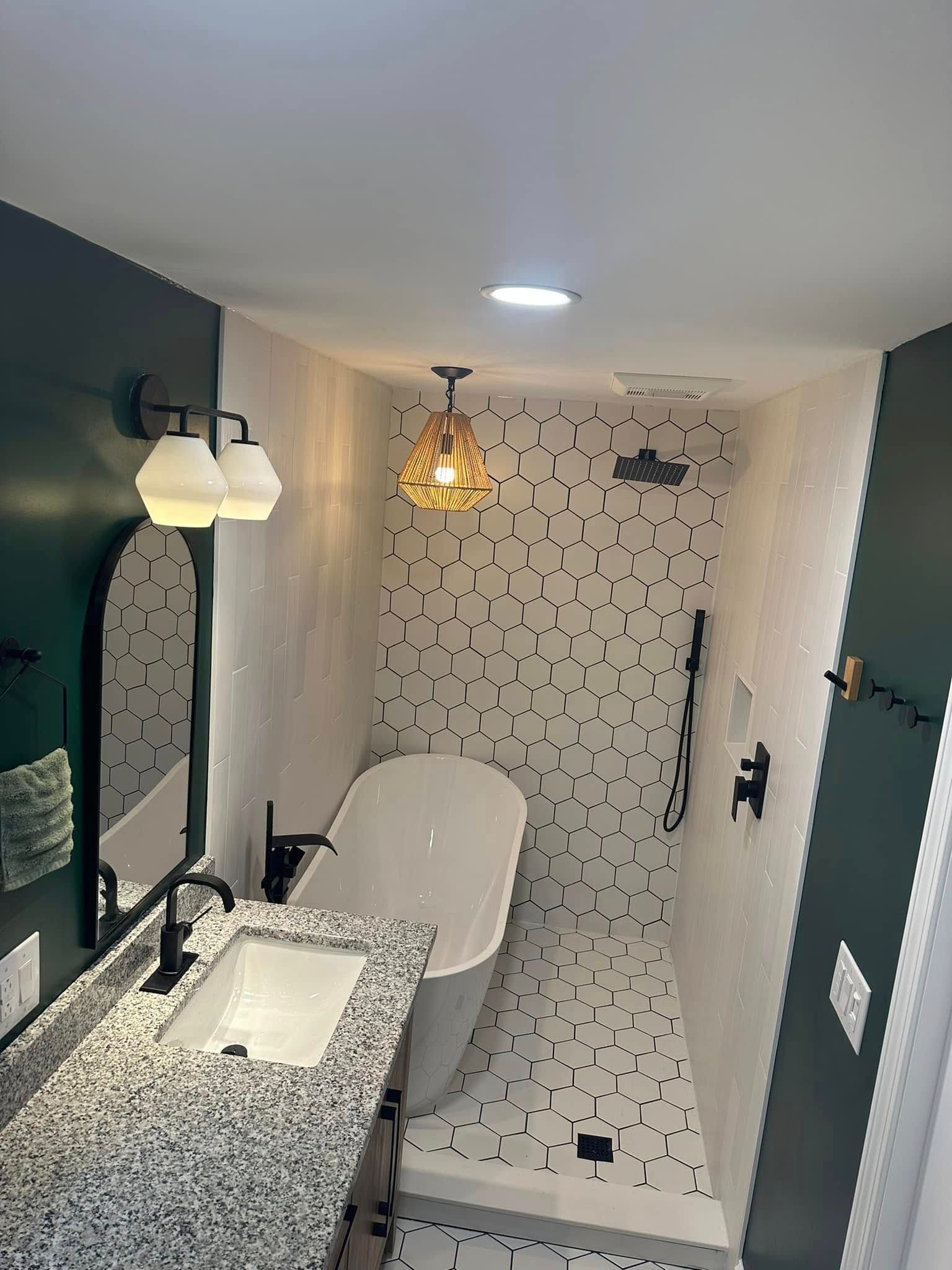 Modern bathroom with a bathtub and a black and white speckled tiled shower.