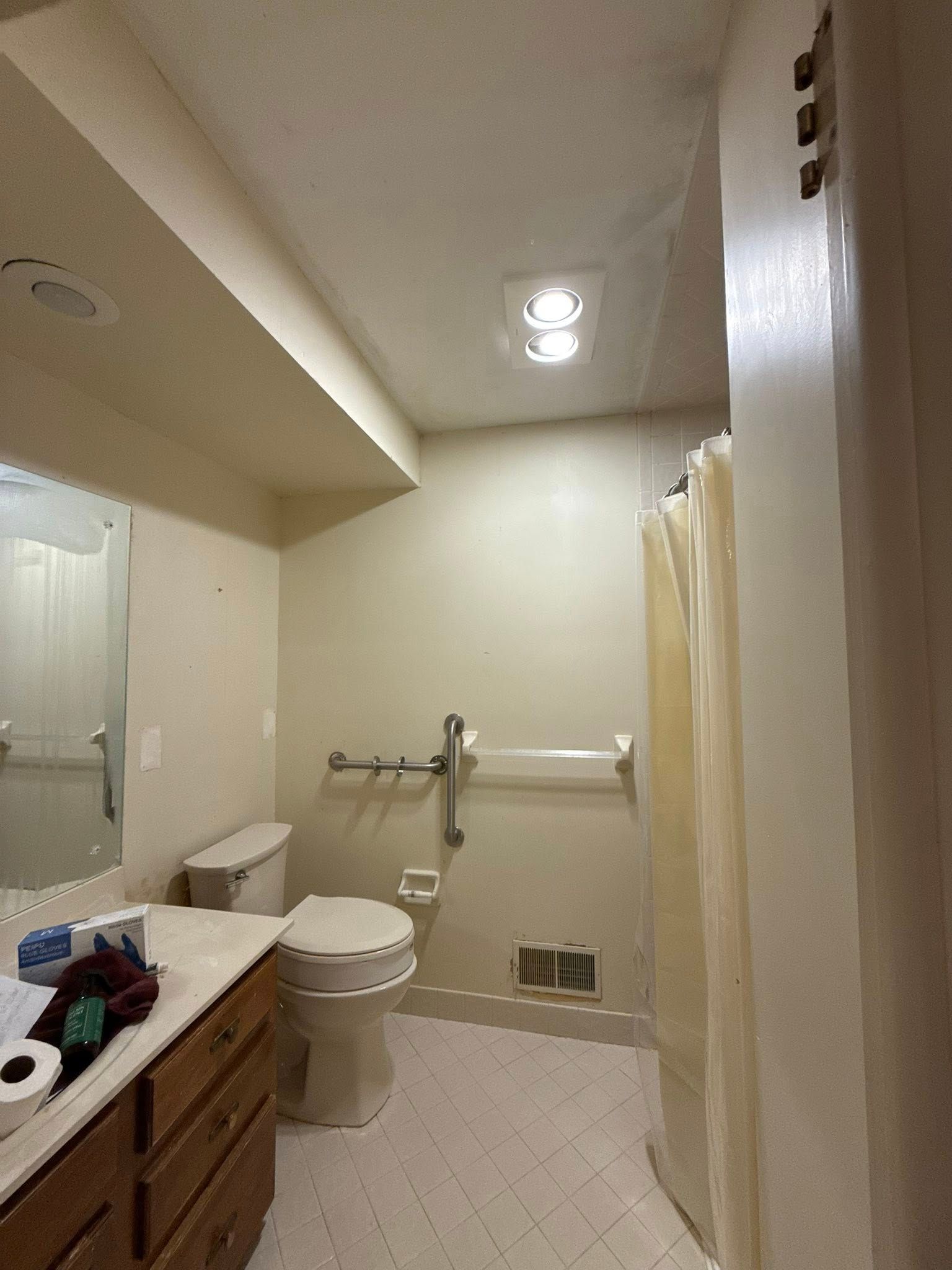 Bathroom with accessible features: grab bars, raised toilet, shower curtain, and a vanity.