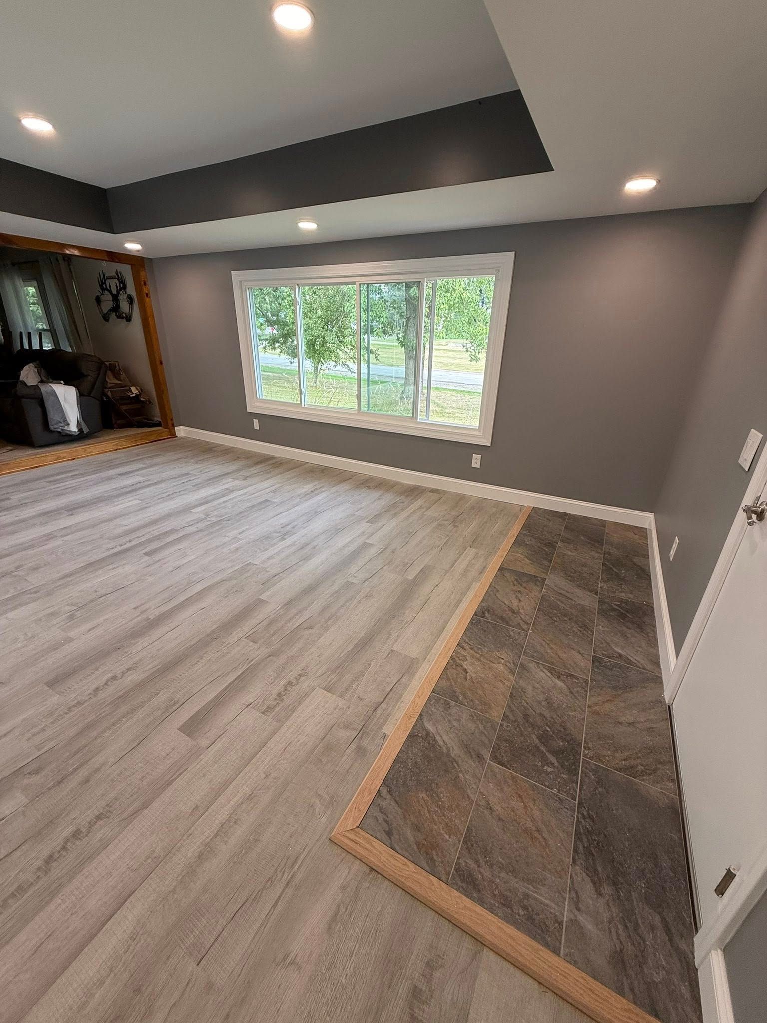 Interior room with gray walls, light wood flooring, and a patterned dark tile border.