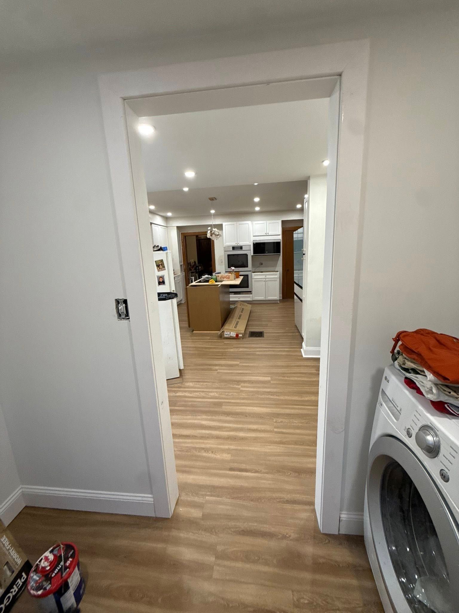 View through doorway into kitchen with appliances and wood flooring.