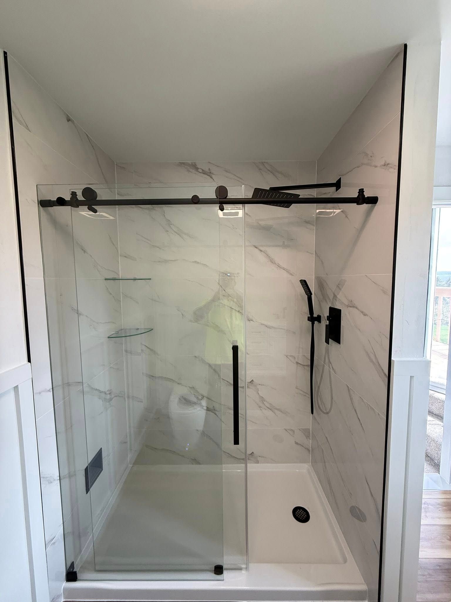 Narrow hallway with hardwood floors and doors on both sides leading to a living area.