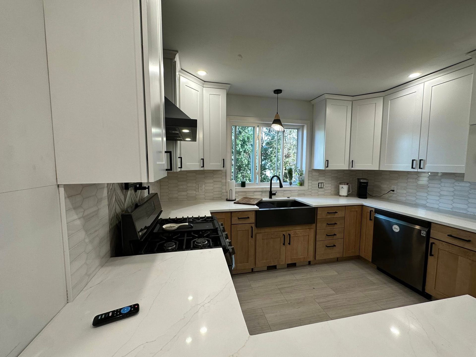 Modern kitchen with white upper cabinets, wood lower cabinets, and stainless steel appliances.