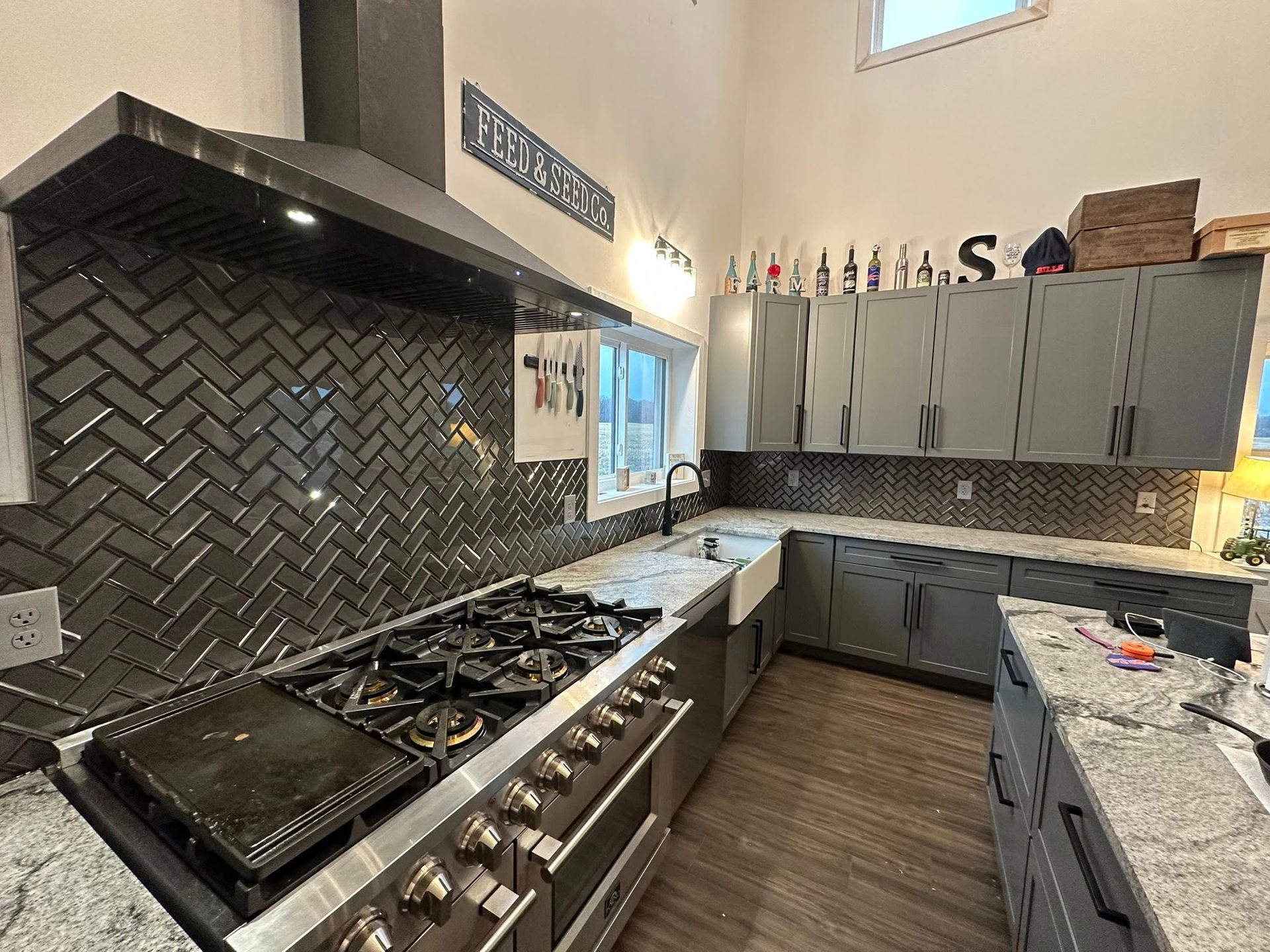 White kitchen with stainless steel appliances, black countertops, and patterned backsplash.