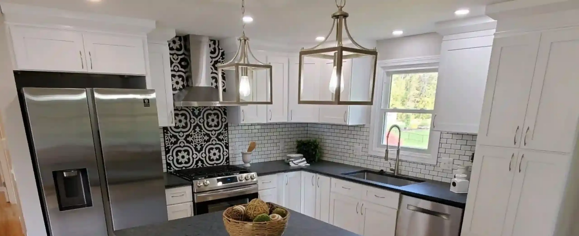 A modern kitchen with white cabinets, stainless steel appliances, and geometric tile backsplash.
