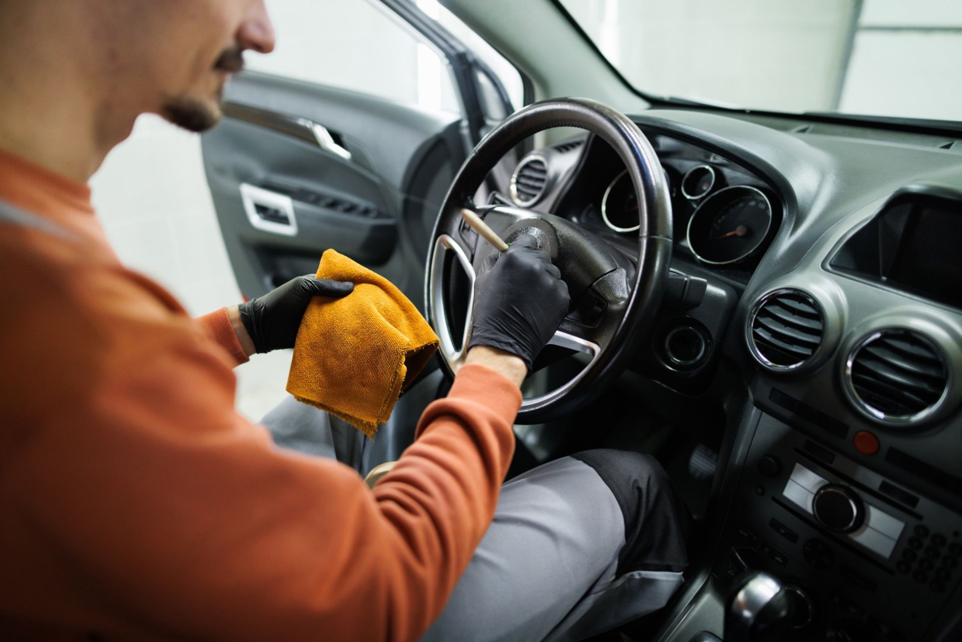 A Man Is Cleaning the Steering Wheel of A Car with A Cloth - Parma, OH - Family First Car Care