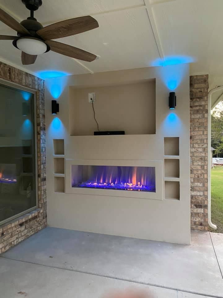 Outdoor entertainment area with fireplace, blue LED lighting, and built-in shelving.