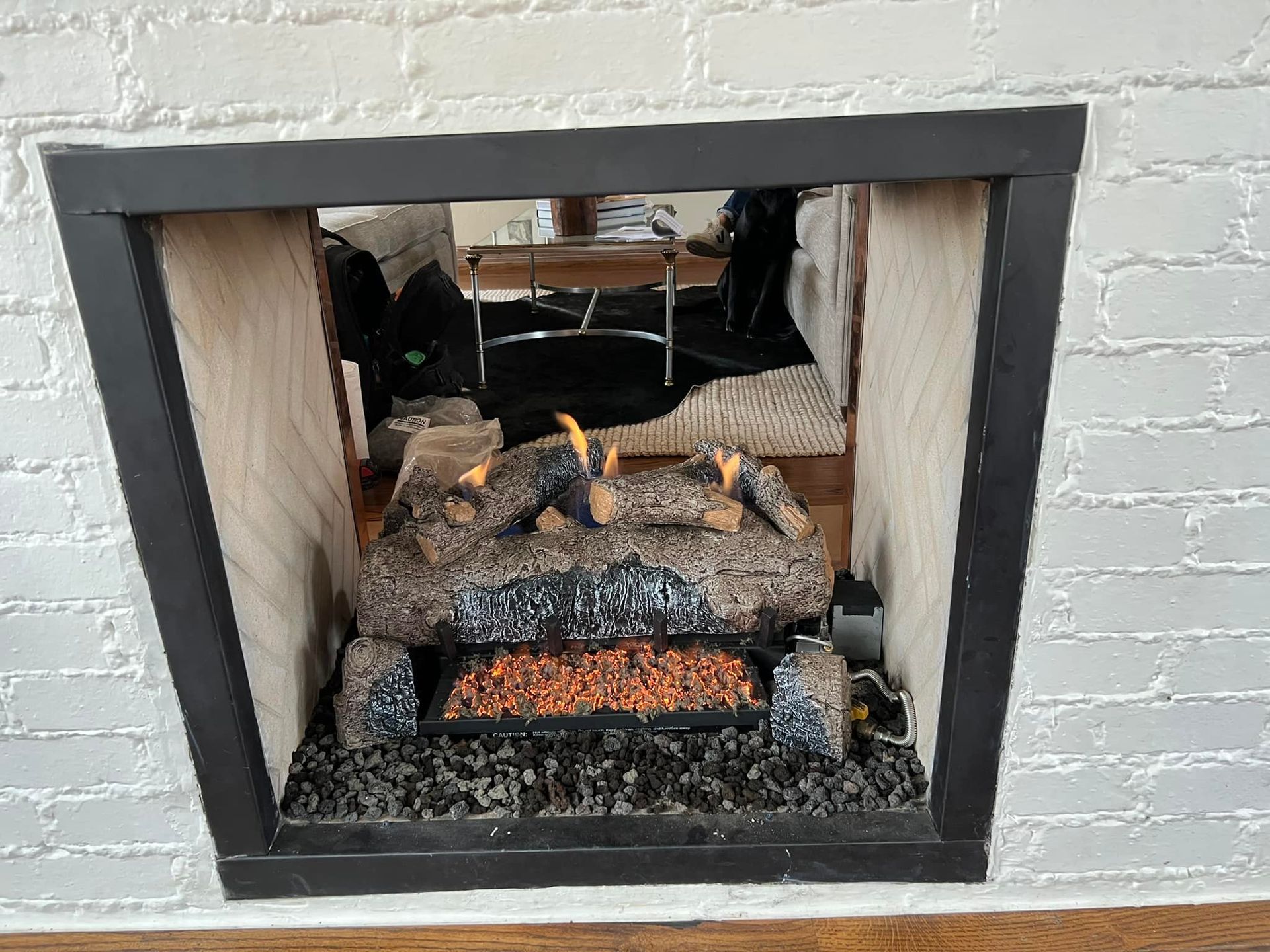 Electric fireplace in a brick-surrounded inset, black trim, with artificial flames and glowing embers. Electric fireplace in a brick-surrounded inset, black trim, with artificial flames and glowing embers.