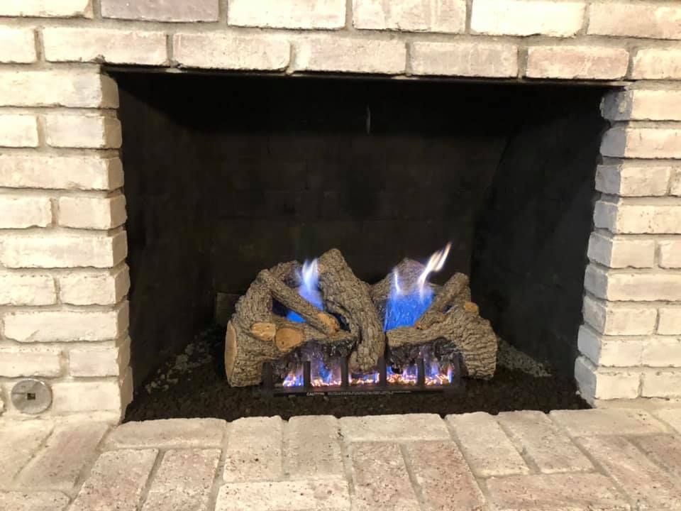 Fireplace with brick surround, gas logs with blue flames.