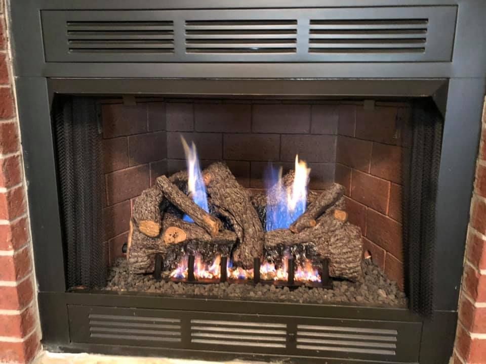Gas fireplace with burning logs and blue flames.