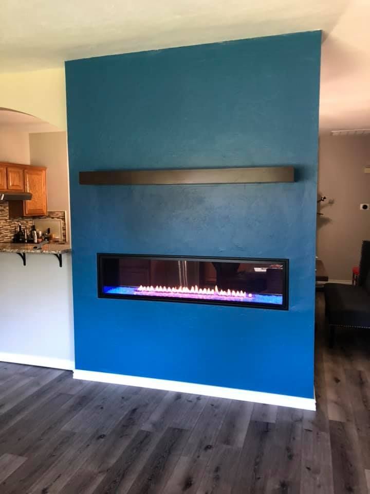 Blue wall with a fireplace and a dark shelf.