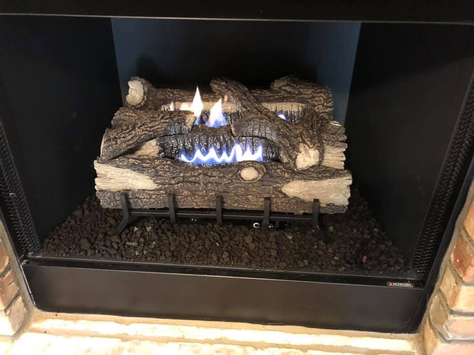 Gas fireplace with faux logs burning with blue and yellow flames, black firebox.