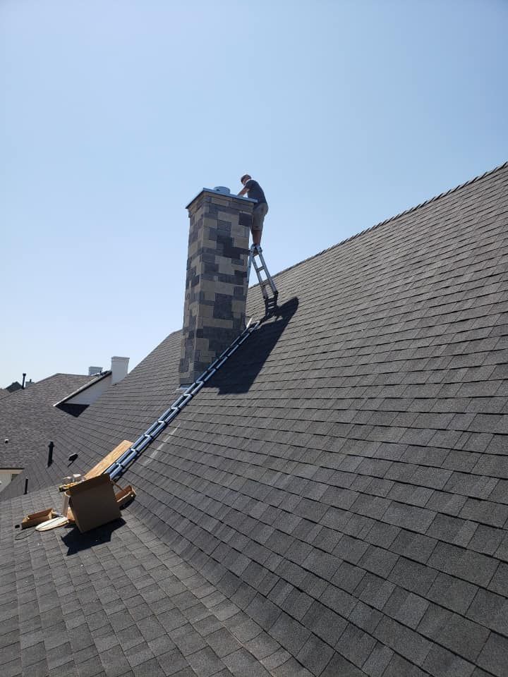Person on ladder repairing chimney on a shingled roof, clear blue sky. Person on ladder repairing chimney on a shingled roof, clear blue sky.