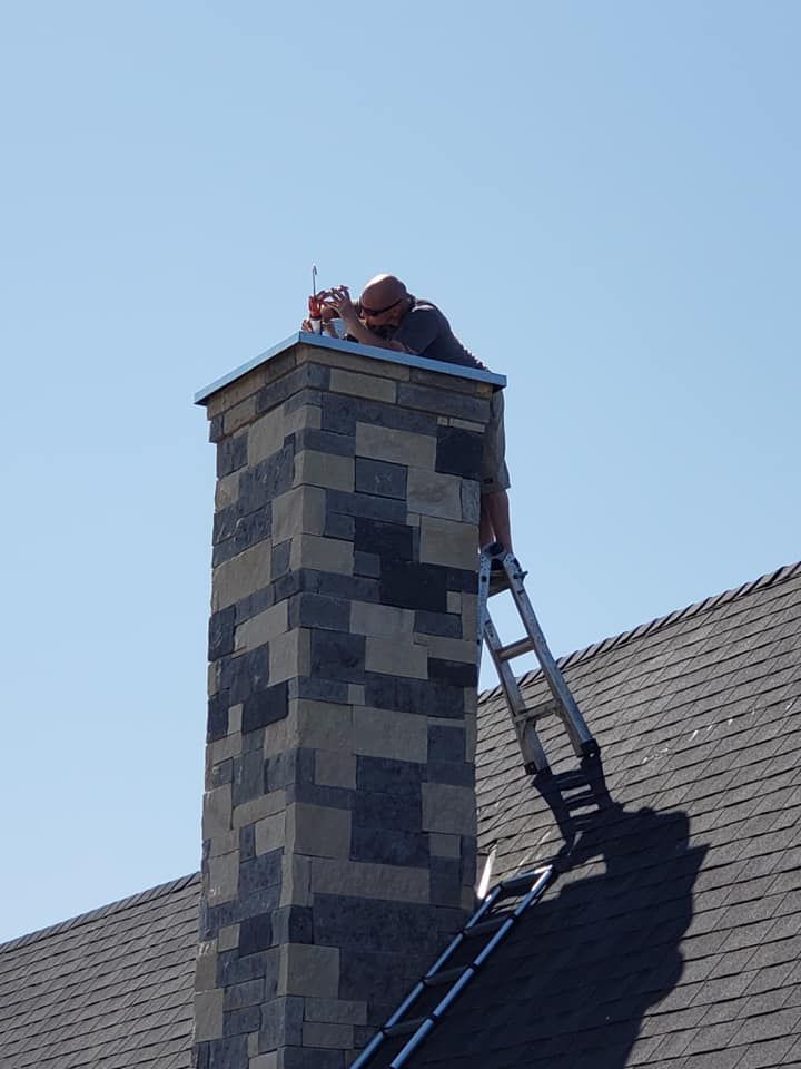 Person on a ladder repairing chimney; clear blue sky.