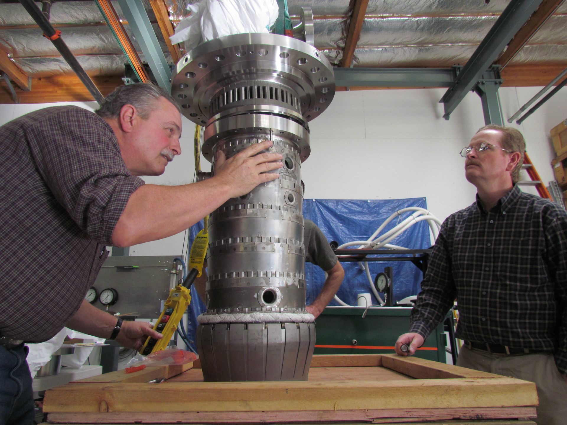 Two men are working on a large metal object