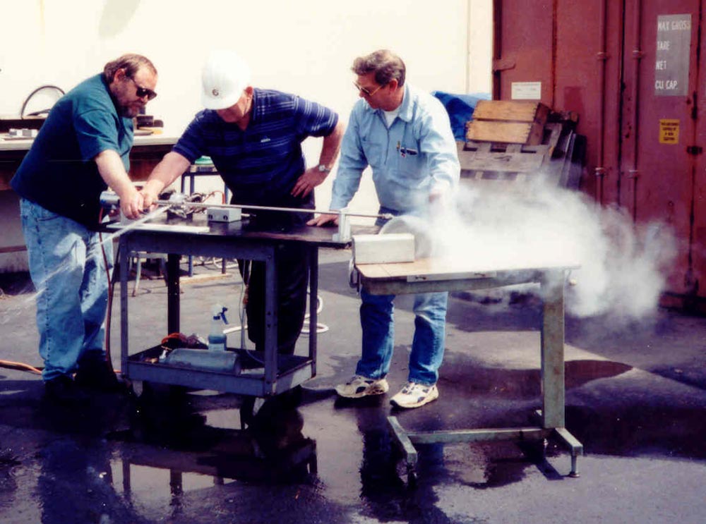 Three men standing around a table with smoke coming out of it