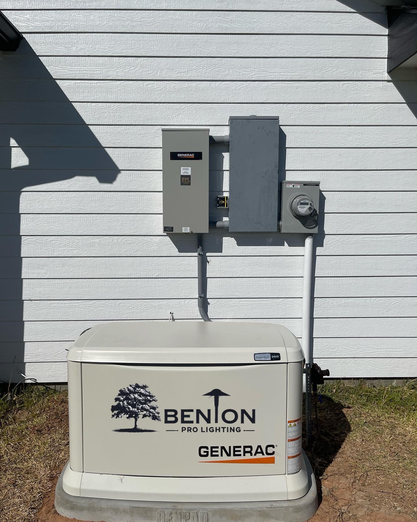 Generator with transfer switch and electrical panel mounted on a white house exterior.