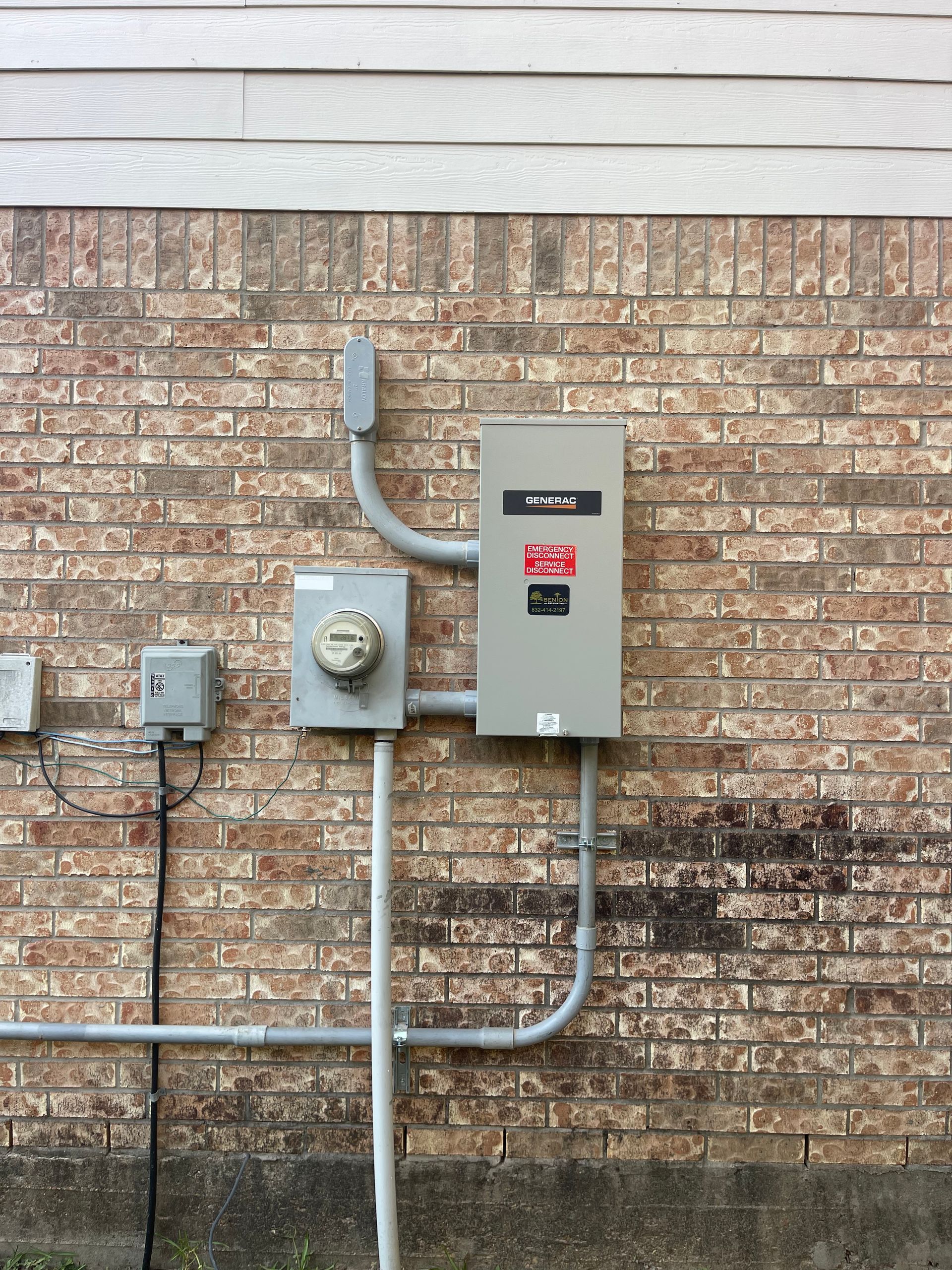 Exterior electrical panel and meter box mounted on a brick wall with gray conduit.