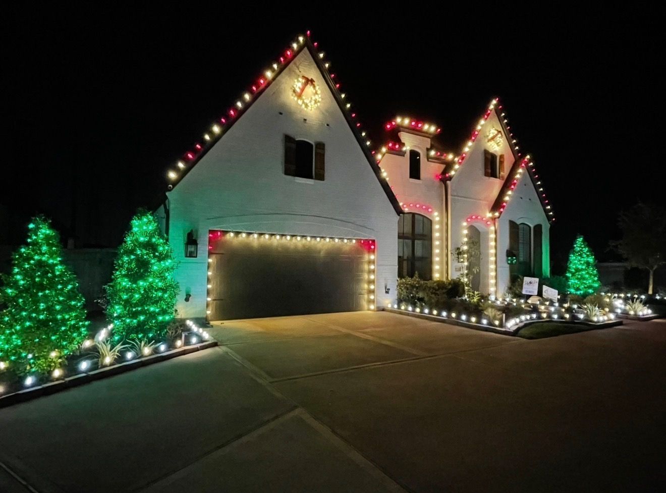 House decorated for Christmas with white roof lights, lawn displays, and colorful lights along the walkway.