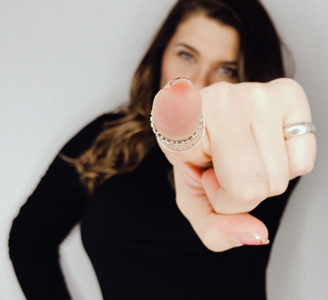 a woman with a ring on her finger pointing at the camera